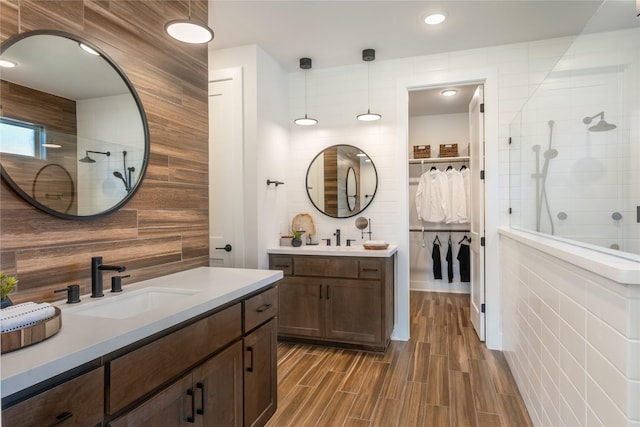 9122 Heckenberg Arbor Ln, Cypress, TX 77433 - full bathroom with two vanities, a tile shower, a spacious closet, wood finished floors, and tile walls