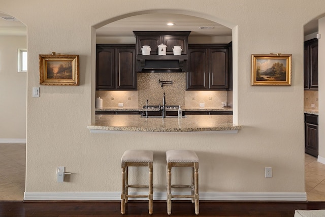 11702 Saporito Way, Richmond, TX 77406 - kitchen with backsplash, dark brown cabinets, a breakfast bar, and a sink