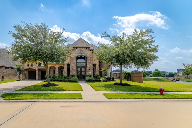 11702 Saporito Way, Richmond, TX 77406 - french country home featuring french doors, a front yard, driveway, an attached garage, and stone siding