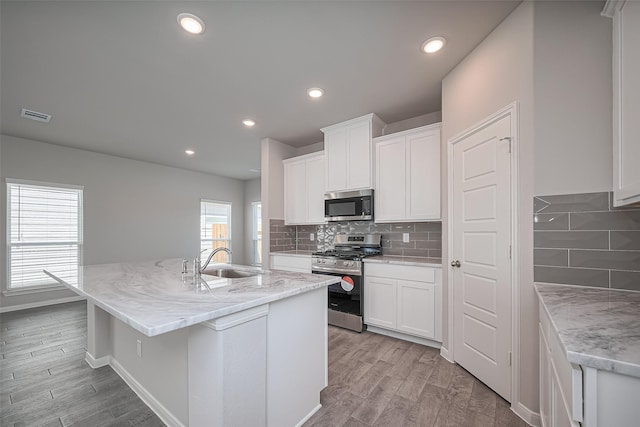 230 Emerald Thicket Ln, Huffman, TX 77336 - kitchen with stainless steel appliances, a sink, light wood-style flooring, a center island with sink, and recessed lighting