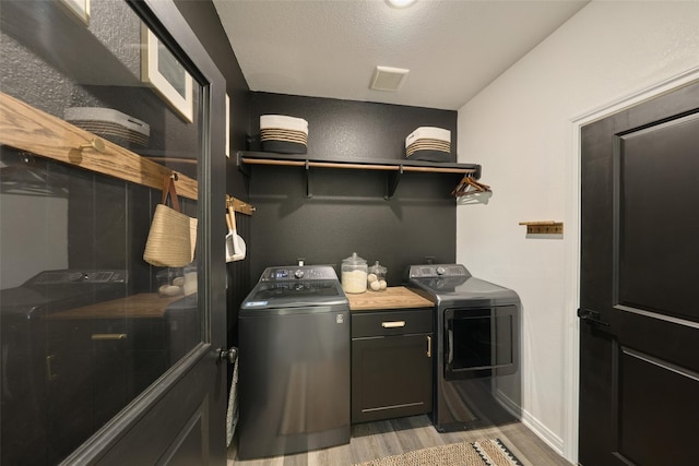 4 Hanover Ln, Panorama Village, TX 77304 - laundry area featuring independent washer and dryer, cabinet space, light wood-style flooring, and baseboards