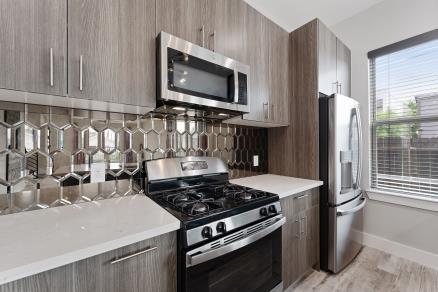 1804 Schweikhardt St, Houston, TX 77020 - kitchen featuring stainless steel appliances, modern cabinets, light countertops, gray cabinetry, and decorative backsplash