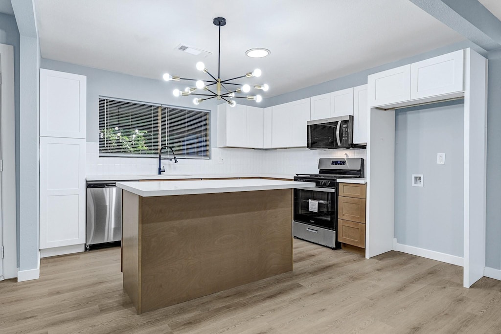 8743 Pattibob St, Houston, TX 77029 - kitchen featuring appliances with stainless steel finishes, a sink, a chandelier, white cabinetry, and a kitchen island