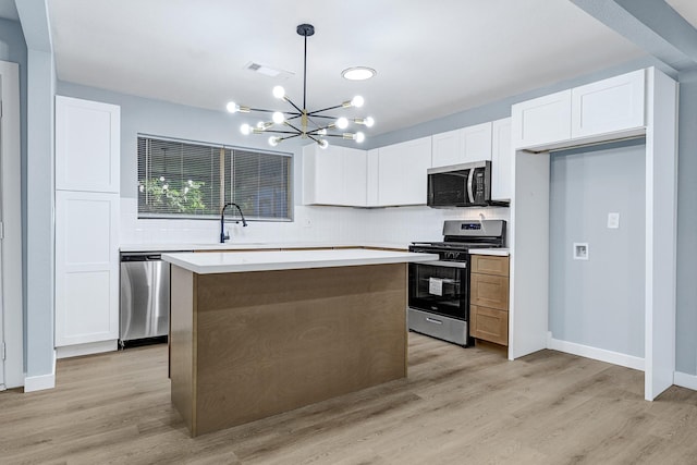 8743 Pattibob St, Houston, TX 77029 - kitchen featuring appliances with stainless steel finishes, a sink, a chandelier, white cabinetry, and a kitchen island