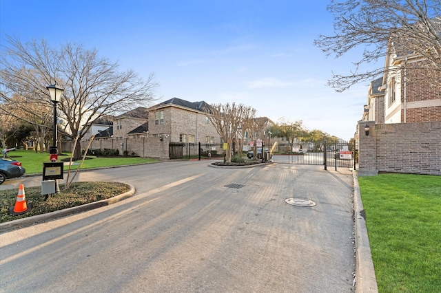 10106 Holly Chase Dr, Houston, TX 77042 - view of asphalt road featuring curbs, a gate, a residential view, street lights, and a gated entry