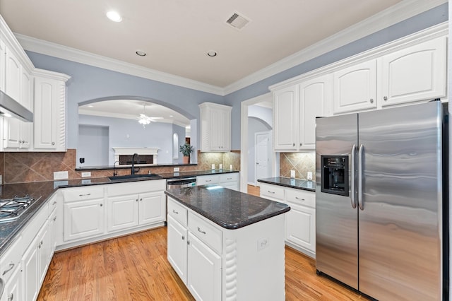 10106 Holly Chase Dr, Houston, TX 77042 - kitchen with stainless steel appliances, a sink, arched walkways, white cabinetry, and light wood-style floors