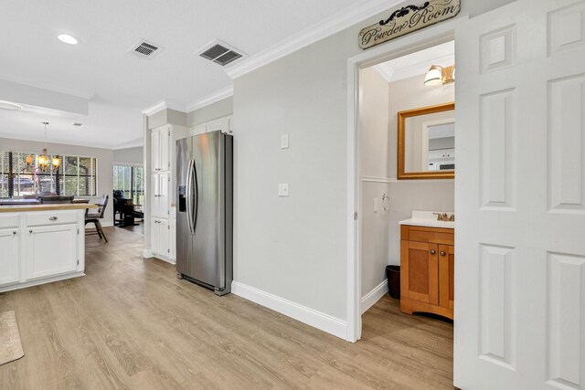 148 S Oak Bluff St, Trinity, TX 75862 - kitchen with stainless steel fridge, ornamental molding, white cabinetry, light wood finished floors, and a chandelier