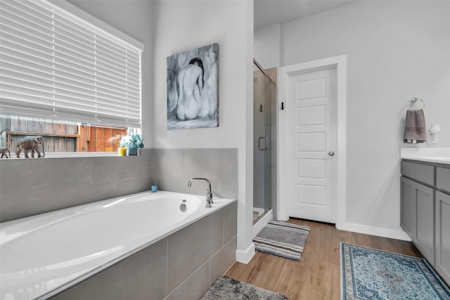 8310 Royal Breeze Dr, Cypress, TX 77433 - bathroom with a shower stall, a garden tub, wood finished floors, baseboards, and vanity