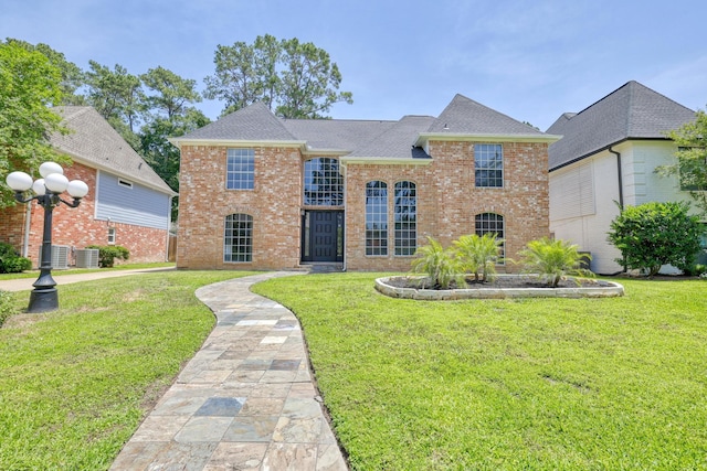 17706 August Meadows Ln, Spring, TX 77379 - view of front facade featuring a front yard, brick siding, central AC unit, and roof with shingles