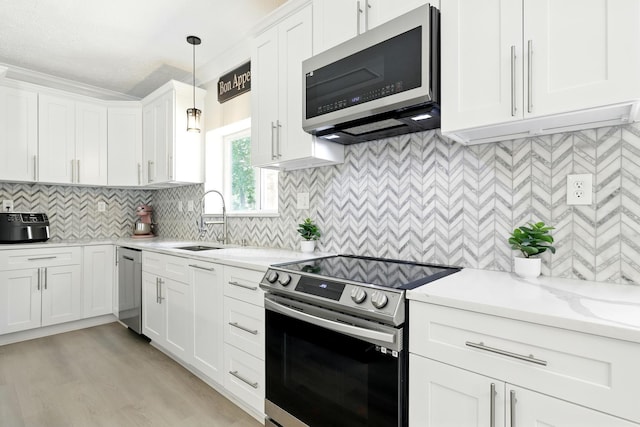 17706 August Meadows Ln, Spring, TX 77379 - kitchen featuring stainless steel appliances, white cabinets, a sink, backsplash, and pendant lighting