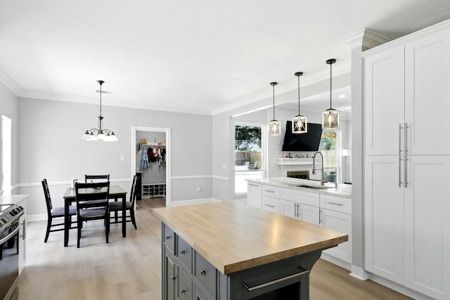 17706 August Meadows Ln, Spring, TX 77379 - kitchen featuring a sink, butcher block counters, a kitchen island, light wood finished floors, and white cabinetry