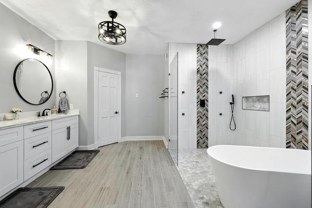 17706 August Meadows Ln, Spring, TX 77379 - bathroom with vanity, a walk in shower, a freestanding bath, wood finished floors, and baseboards