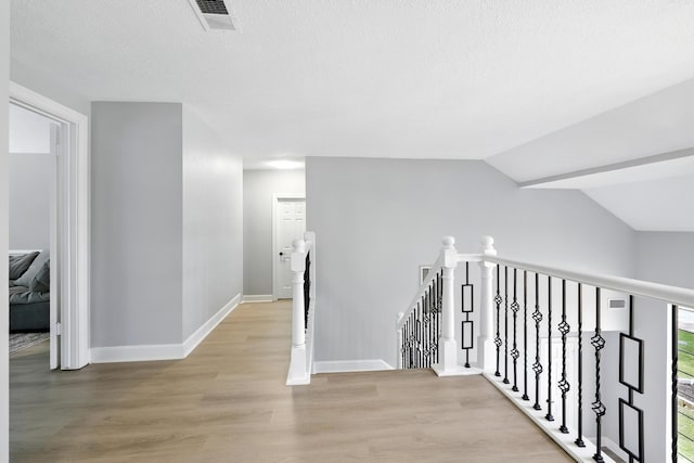 17706 August Meadows Ln, Spring, TX 77379 - corridor with an upstairs landing, light wood-style flooring, baseboards, a textured ceiling, and vaulted ceiling