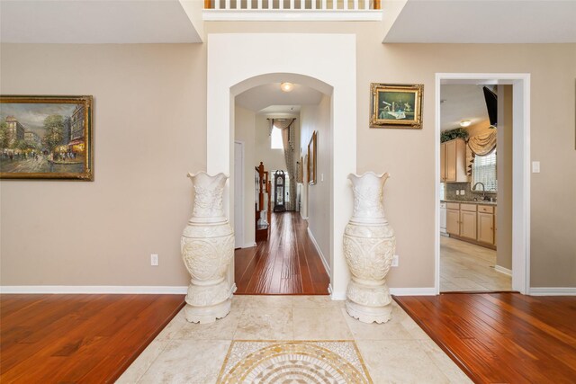 6610 Golden View Ct, Houston, TX 77083 - hallway with arched walkways, light wood-type flooring, a sink, and baseboards