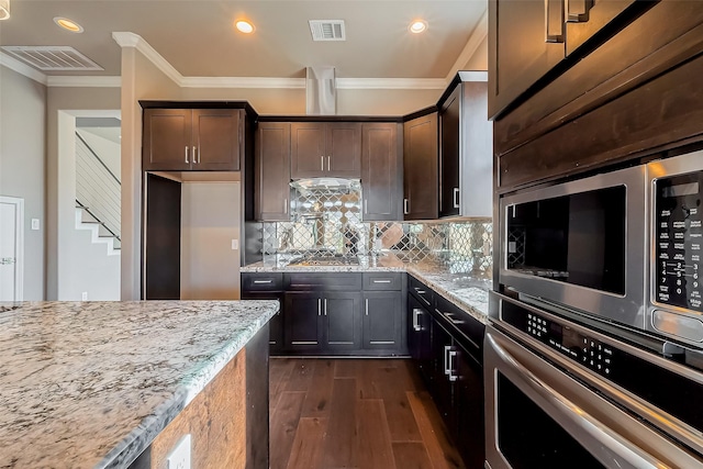 4307 Hershe St, Houston, TX 77020 - kitchen with stainless steel appliances, dark wood finished floors, light stone counters, decorative backsplash, and ornamental molding