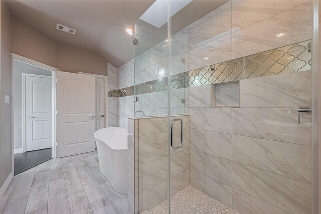 4307 Hershe St, Houston, TX 77020 - full bath featuring lofted ceiling, a soaking tub, a shower stall, and wood finished floors