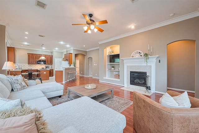 2500 Amy Lee Dr, Conroe, TX 77304 - living area with arched walkways, ceiling fan, built in shelves, light wood finished floors, and crown molding