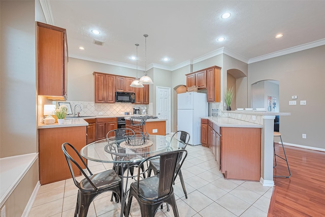 2500 Amy Lee Dr, Conroe, TX 77304 - kitchen with freestanding refrigerator, black microwave, a peninsula, brown cabinets, and arched walkways