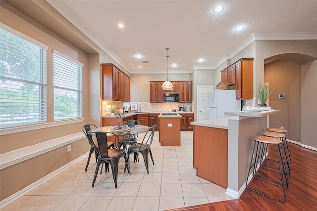 2500 Amy Lee Dr, Conroe, TX 77304 - kitchen with black microwave, freestanding refrigerator, brown cabinets, arched walkways, and a peninsula