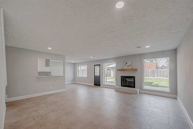 9602 John Bank Dr, Spring, TX 77379 - unfurnished living room with baseboards, a textured ceiling, light tile patterned flooring, recessed lighting, and a fireplace