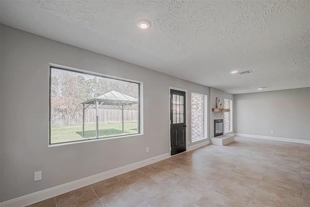 9602 John Bank Dr, Spring, TX 77379 - unfurnished living room with a textured ceiling, plenty of natural light, a fireplace, baseboards, and recessed lighting