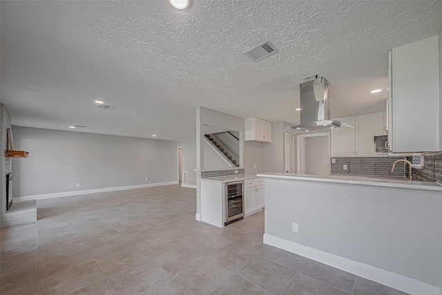 9602 John Bank Dr, Spring, TX 77379 - kitchen with island range hood, stainless steel microwave, open floor plan, tasteful backsplash, and wine cooler