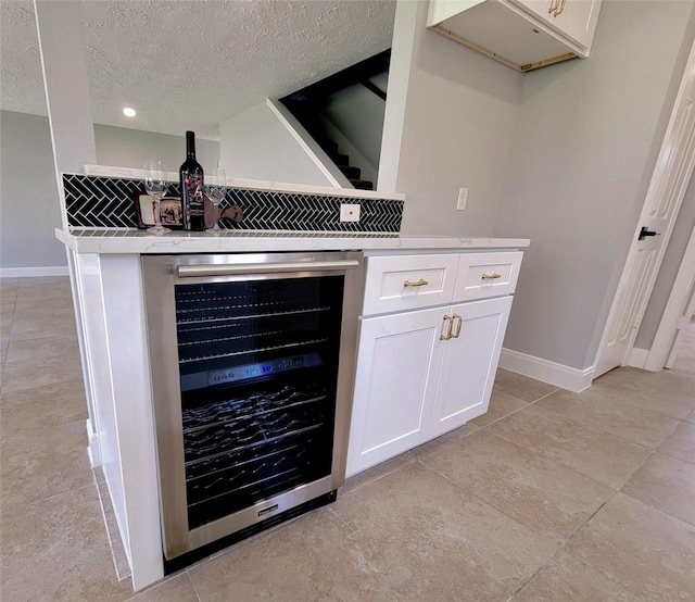 9602 John Bank Dr, Spring, TX 77379 - detailed view of wine cooler, a dry bar, baseboards, a textured ceiling, and decorative backsplash