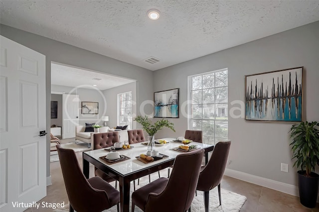 9602 John Bank Dr, Spring, TX 77379 - dining area with baseboards, a textured ceiling, and light tile patterned flooring