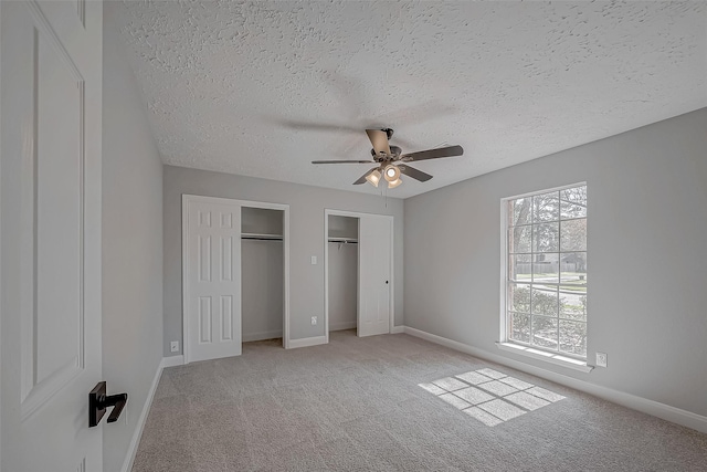 9602 John Bank Dr, Spring, TX 77379 - unfurnished bedroom featuring two closets, a textured ceiling, light carpet, baseboards, and ceiling fan