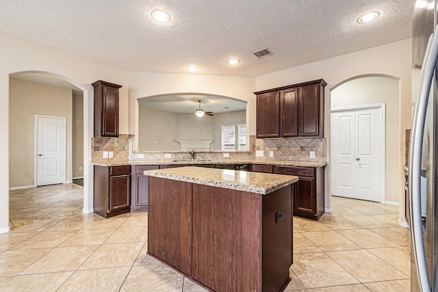 30710 Basil Trace Dr, Spring, TX 77386 - kitchen featuring ceiling fan, a sink, arched walkways, decorative backsplash, and a kitchen island