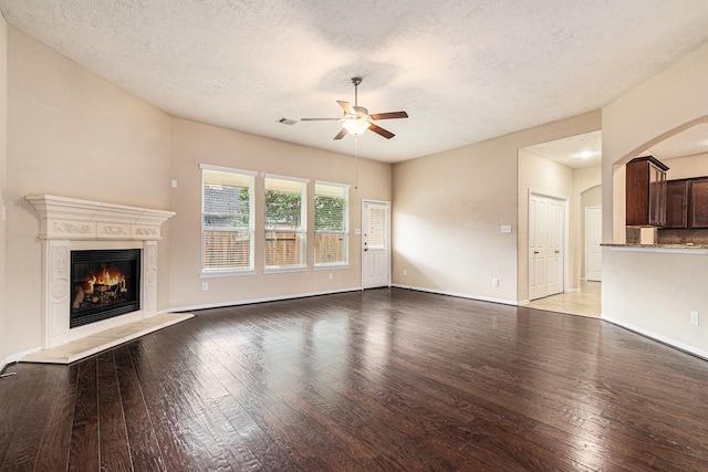 30710 Basil Trace Dr, Spring, TX 77386 - unfurnished living room featuring a ceiling fan, hardwood / wood-style flooring, a fireplace, a textured ceiling, and arched walkways