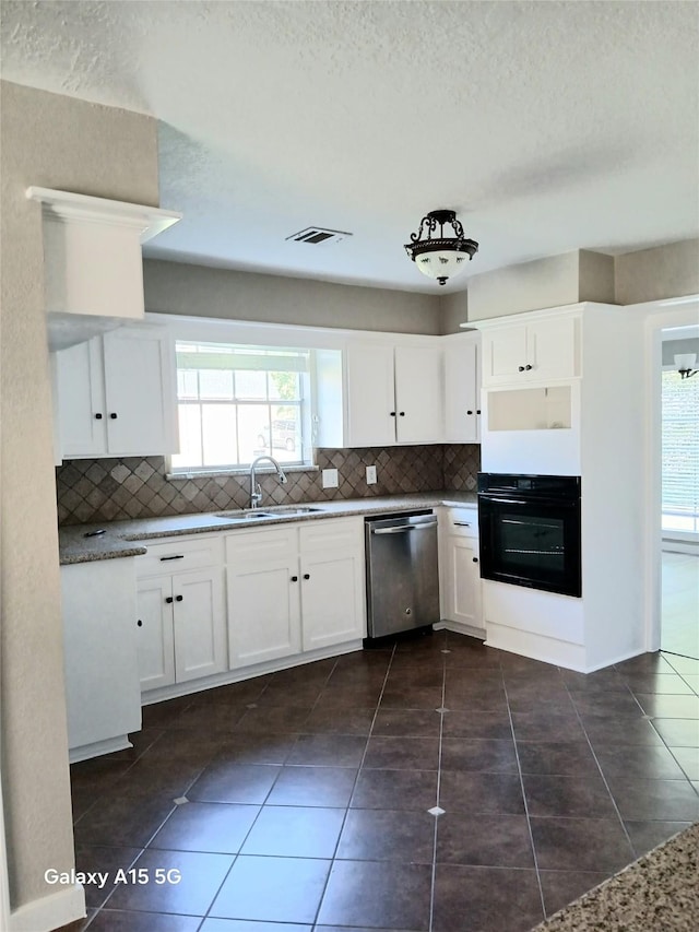 17931 Elk River Cir, Houston, TX 77090 - kitchen featuring stainless steel dishwasher, black oven, a sink, decorative backsplash, and a textured ceiling