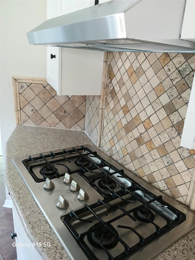 17931 Elk River Cir, Houston, TX 77090 - kitchen view of range hood, stainless steel gas stovetop, white cabinetry, and decorative backsplash
