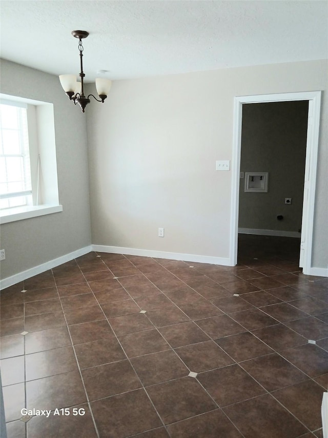 17931 Elk River Cir, Houston, TX 77090 - spare room with a chandelier, dark tile patterned floors, and baseboards