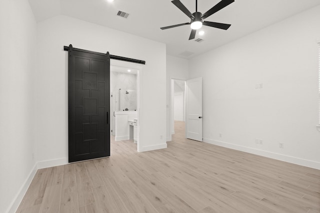 16154 Rustling Woods Rd, Conroe, TX 77302 - unfurnished bedroom featuring light wood-style flooring, a barn door, baseboards, lofted ceiling, and ensuite bath