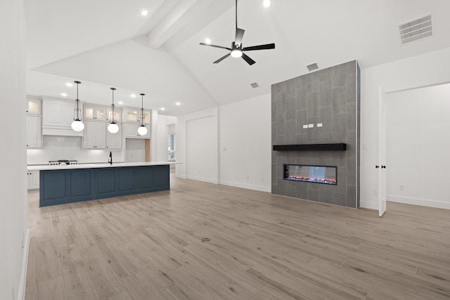 16154 Rustling Woods Rd, Conroe, TX 77302 - unfurnished living room featuring a ceiling fan, light wood-type flooring, beam ceiling, baseboards, and a fireplace