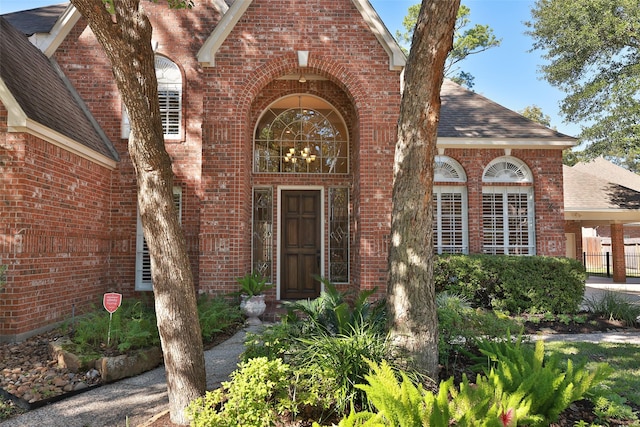 6910 Amber Ct, Houston, TX 77069 - property entrance featuring a shingled roof and brick siding