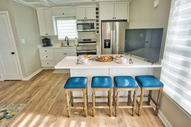 450 County Road 206, Sargent, TX 77414 - kitchen with appliances with stainless steel finishes, a sink, a kitchen breakfast bar, light wood-style floors, and baseboards