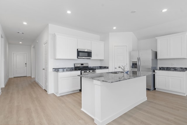 305 Robin St, Angleton, TX 77515 - kitchen with appliances with stainless steel finishes, a sink, dark stone counters, a center island with sink, and light wood-style floors