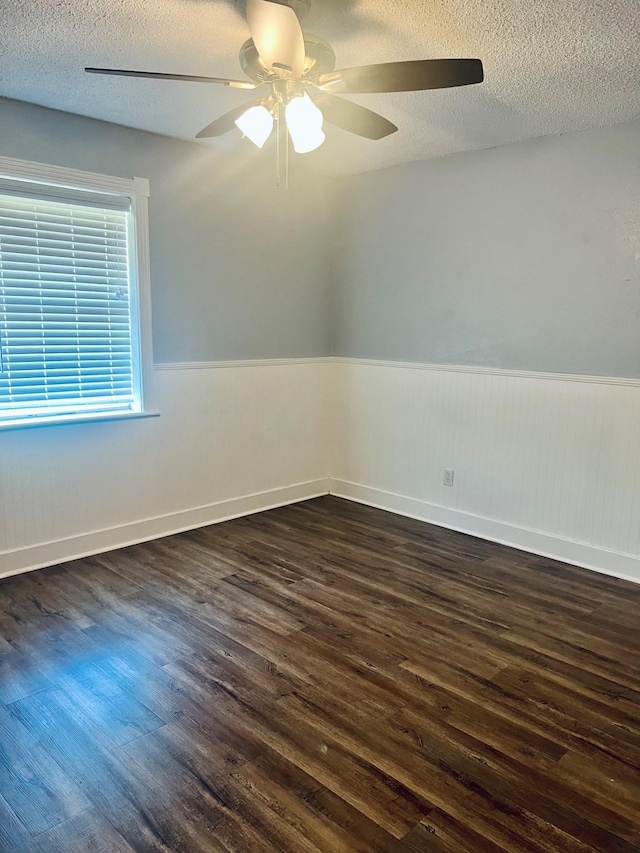 1301 Cherie Brook Dr, Goliad, TX 77963 - spare room with dark wood-type flooring, wainscoting, ceiling fan, a textured ceiling, and baseboards