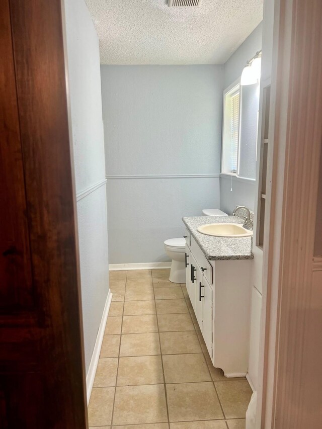 1301 Cherie Brook Dr, Goliad, TX 77963 - bathroom with a textured ceiling, tile patterned flooring, toilet, and vanity