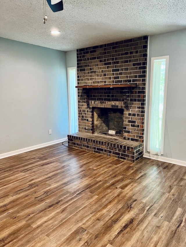 1301 Cherie Brook Dr, Goliad, TX 77963 - unfurnished living room featuring wood finished floors, a textured ceiling, baseboards, and a fireplace