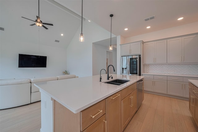 2610 Texas Orange Trl, Richmond, TX 77406 - kitchen featuring appliances with stainless steel finishes, a sink, open floor plan, light wood-type flooring, and decorative backsplash
