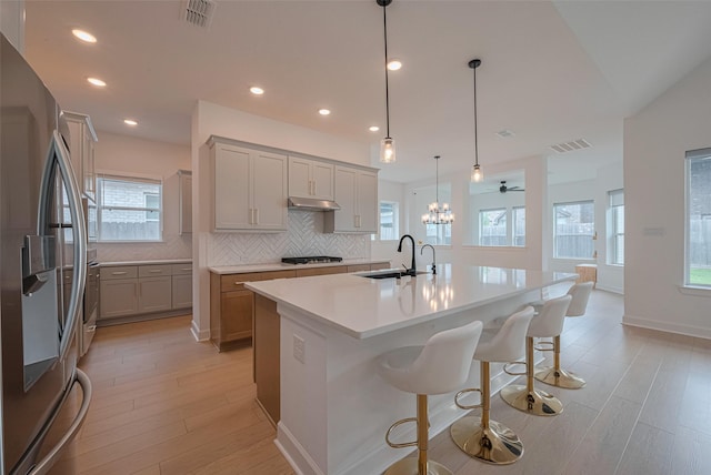 2610 Texas Orange Trl, Richmond, TX 77406 - kitchen featuring stainless steel fridge with ice dispenser, a sink, gas cooktop, backsplash, and under cabinet range hood