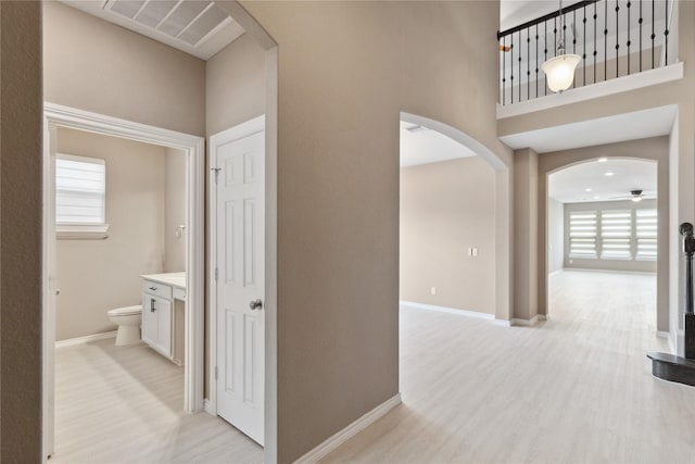 24730 Harbor Terrace Ln, Richmond, TX 77406 - hallway featuring arched walkways, healthy amount of natural light, light wood-style flooring, baseboards, and a towering ceiling