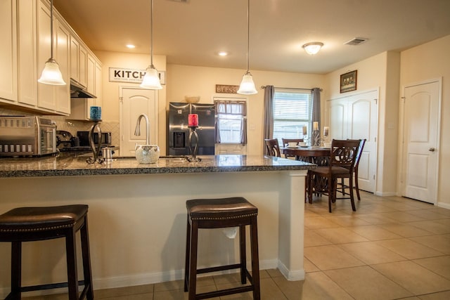 7735 Nevaeh Crest Path, Houston, TX 77016 - kitchen featuring appliances with stainless steel finishes, a peninsula, light tile patterned floors, a breakfast bar area, and recessed lighting