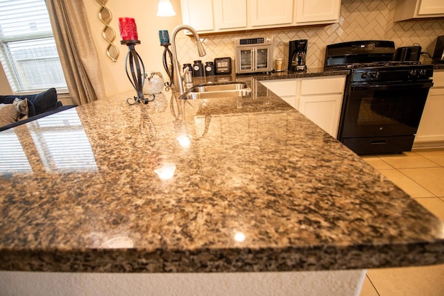 7735 Nevaeh Crest Path, Houston, TX 77016 - kitchen featuring black range with gas stovetop, dark stone counters, tasteful backsplash, white cabinetry, and a sink