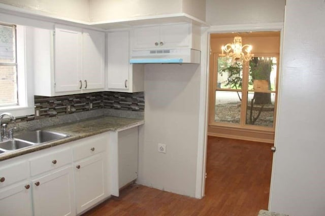 4906 Havenwoods Dr, Houston, TX 77066 - kitchen featuring under cabinet range hood, a sink, a chandelier, wood finished floors, and white cabinetry