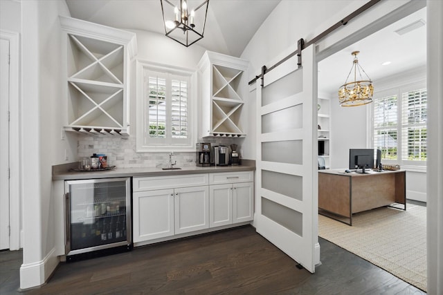 indoor bar with a chandelier, wine cooler, dark wood finished floors, decorative backsplash, and vaulted ceiling