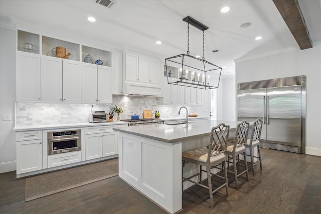 kitchen with stainless steel appliances, a sink, tasteful backsplash, light countertops, and ornamental molding